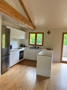 a large kitchen with white cabinets and a wooden floor at Chalet 6 personnes ou studio 2 personnes in Ax-les-Thermes +17 photos