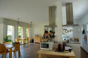 two people sitting in a kitchen with a microwave at Ostello Cresciano in Cresciano