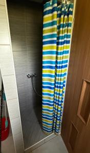 a shower with a yellow and blue striped shower curtain at Domki Brzozowy Zakątek in Sochy +28 photos