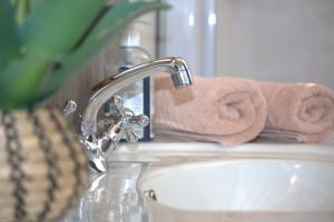 a bathroom sink with a faucet and towels at Villa Mariss Guesthouse in Kraaifontein +81 photos