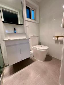 a white bathroom with a toilet and a sink at Willows Motel in Goulburn +73 photos