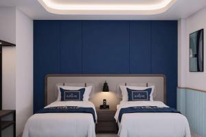 two beds in a room with blue walls at du PALAIS Hotel in Sultan Thaha Airport +26 photos