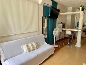 a living room with a white couch and a tv at Departamento chichan nah in Progreso