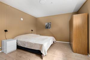 a bedroom with a white bed and a wooden cabinet at Beach cottage in Søgne in Kristiansand +7 photos