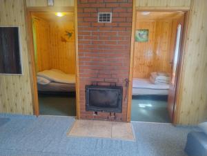 a brick fireplace in a room with two beds at Domek nad jeziorem -Mazury- Linia Brzegowa in Piotrowice
