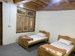 two beds in a room with a window at Kalash Echo Lodge in Chitral