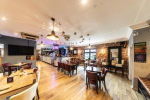 a restaurant with tables and chairs and a bar at Littleover Lodge Hotel in Derby