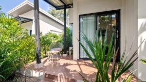 a patio with a chair and some plants at La Casa Bangtao Resort in Ban Thalat Choeng Thale