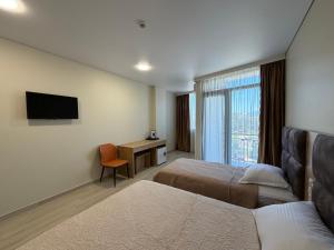 a hotel room with two beds and a television at Hotel Royal Georgia 2 in Batumi