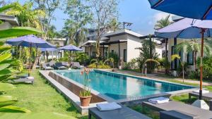 a pool at a resort with chairs and umbrellas at La Casa Bangtao Resort in Ban Thalat Choeng Thale