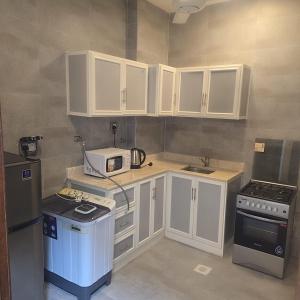 a small kitchen with white cabinets and a microwave at Golden Seasons Rose in Salalah