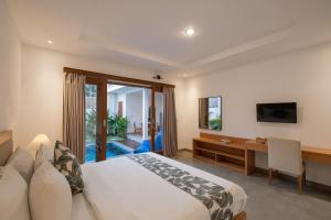 a hotel room with a bed and a desk and a window at Emerald Villas Canggu in Canggu