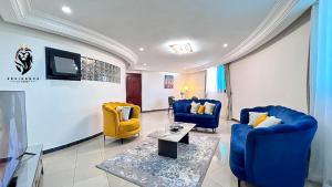 a living room with two blue chairs and a tv at Residence Le Carat in Douala