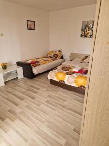 two beds in a room with wooden floors at apartament maia 2 in Turda +1 photo