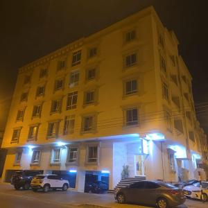 a yellow building with cars parked in front of it at Golden Seasons Rose in Salalah