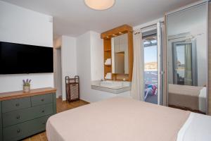 a bedroom with a bed and a tv and a window at Whisper Villa Mykonos in Ano Mera