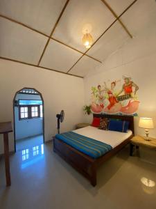 a bedroom with a bed with a painting on the wall at Indiana villa Koggala in Koggala