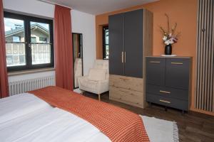 a bedroom with a bed and a cabinet and a chair at Eldorado - Ferienwohnungen & Suiten in Bolsterlang