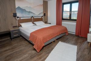 a bedroom with a bed with an orange blanket on it at Eldorado - Ferienwohnungen & Suiten in Bolsterlang
