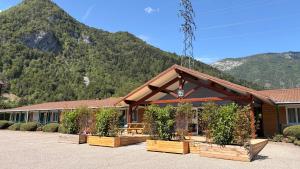 a building with potted plants in front of a mountain at Fasthotel Thones in Thônes