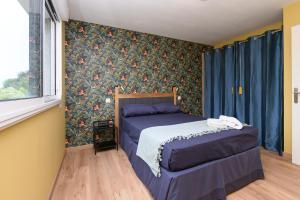 a bedroom with a bed and a window with blue curtains at Le Rockin' Chair in Surzur