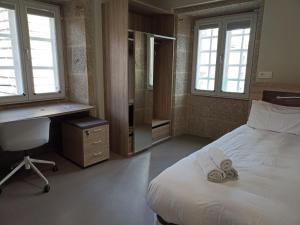 a bedroom with a bed and a desk and windows at Loureiros Dorm in Santiago de Compostela
