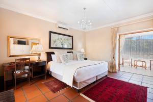 a bedroom with a bed and a desk and a window at Oue Werf Country House in Oudtshoorn +34 photos