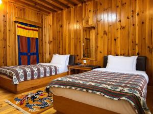 two beds in a room with wooden walls at Risum Resort in Ha