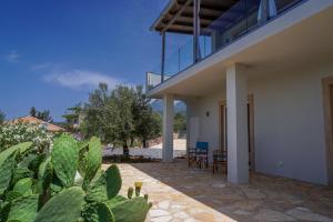 a patio of a house with chairs and cactus at Philia-Modern Living with Panoramic Sea View in Kotrónion
