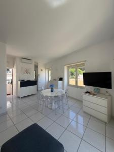 a white living room with a table and a tv at Capresella luxury apartment in Capri