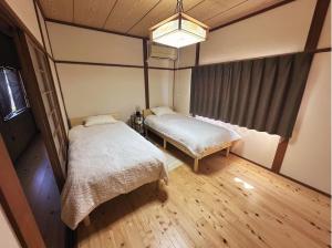 a bedroom with two beds and a chandelier at MIYABI stay house in Tamana