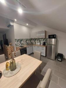 a kitchen with a wooden table and a refrigerator at Gilbert Apartman in Doboz