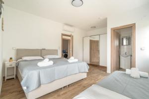 a white bedroom with two beds and a mirror at Perseus in Cape Sarakiniko in Argostoli