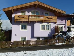 a purple house with a wooden fence in the snow at Landhaus Nageler in Westendorf