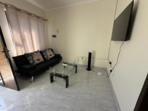 a living room with a black couch and a flat screen tv at Coastwave Guesthouse CBD in Walvis Bay