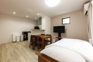 a bedroom with a bed and a table and a kitchen at Anecis名楽町 in Nagoya