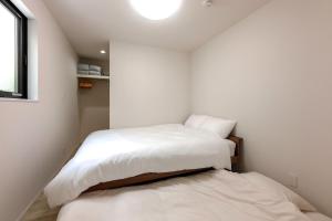 two beds in a small room with white walls at Anecis名楽町 in Nagoya