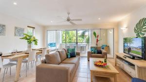 a living room with a couch and a dining room at Cayman Villas Port Douglas in Port Douglas