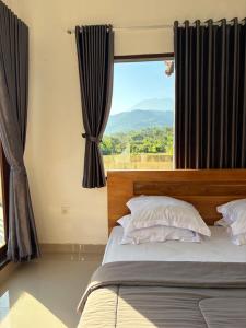 a bedroom with a bed with a large window at Qiana House in Manggis