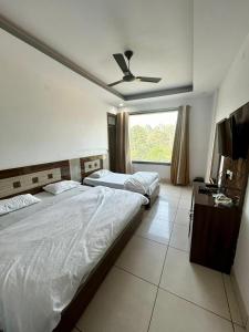 a bedroom with two beds and a ceiling fan at Laksh hotel,Proprietor Dilbag in Kurukshetra