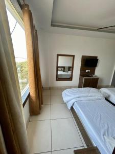 a bedroom with two beds and a mirror and a window at Laksh hotel,Proprietor Dilbag in Kurukshetra