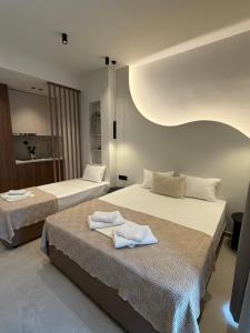 two beds in a hotel room with towels on them at Villa Hara Suites in Paralia Katerinis