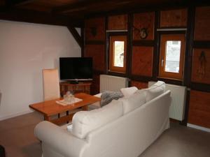 a living room with a white couch and a table at Ferienwohnungen Am Nussbaum in Saalfeld