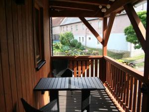 a wooden porch with a table and chairs on a balcony at Ferienwohnungen Am Nussbaum in Saalfeld