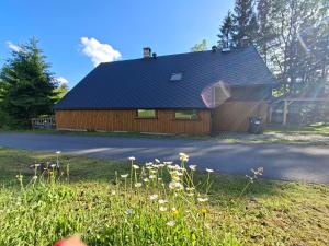 a house with a black roof and a yard with flowers at Chalupa Rumovka in Ostružná