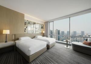 two beds in a hotel room with a large window at Hyatt Regency Suzhou in Suzhou