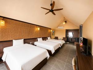 a hotel room with three beds and a ceiling fan at Chuồn Chuồn Resort Nghia Lo - Free Sauna & Onsen in Yên Bái