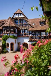 a large building with a balcony and pink flowers at Maison Kieffer - Hotel & Vins d'Alsace in Itterswiller