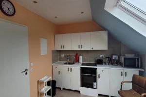a kitchen with white cabinets and a clock on the wall at Privilege - Viel inklusiv! in Viersen