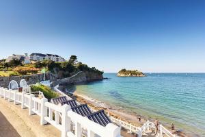 a beach with blue and white chairs and the ocean at L'impasse temps in Saint-Quay-Portrieux